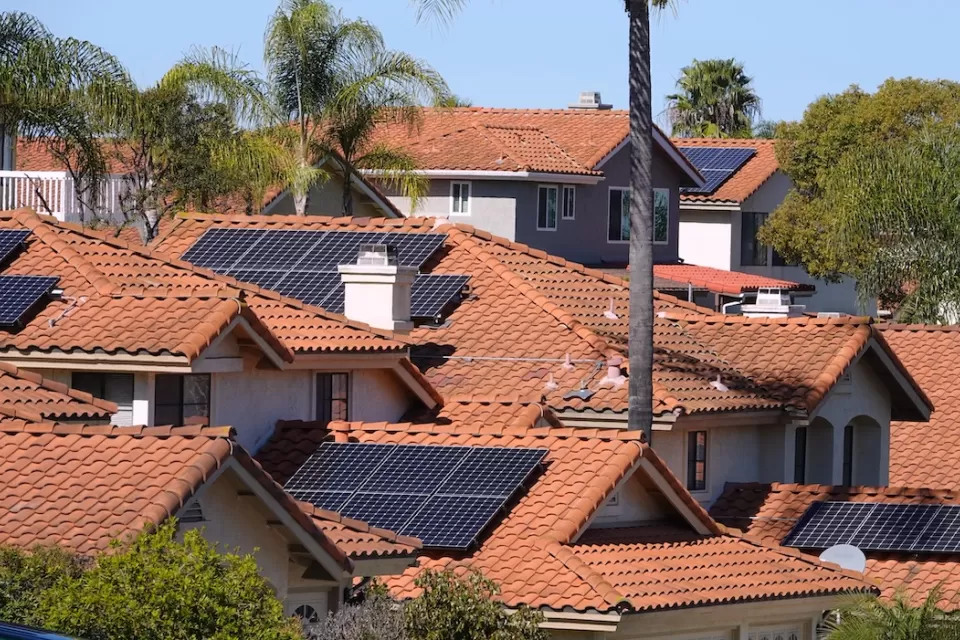 Photovoltaic solar panels on red-tile rooftops in California neighborhood.